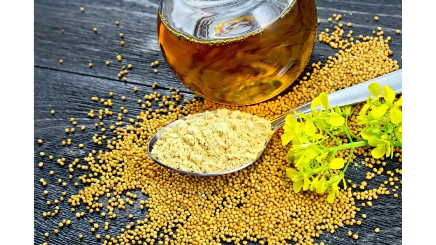 mustard-powder-in-spoon-with-oil-and-flower-on-black-board